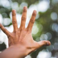 hand outstretched against blurry trees background