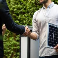 man holding solar panel shaking hand