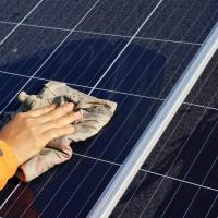 hand using cloth to wipe solar panel