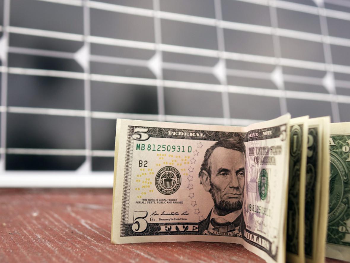 American dollars in front of solar panels, solar savings