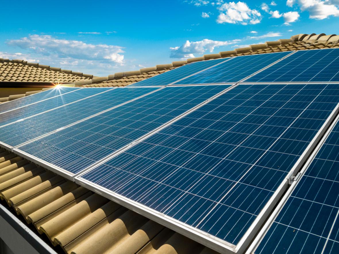 solar panels on a red roof with the sun shining on them