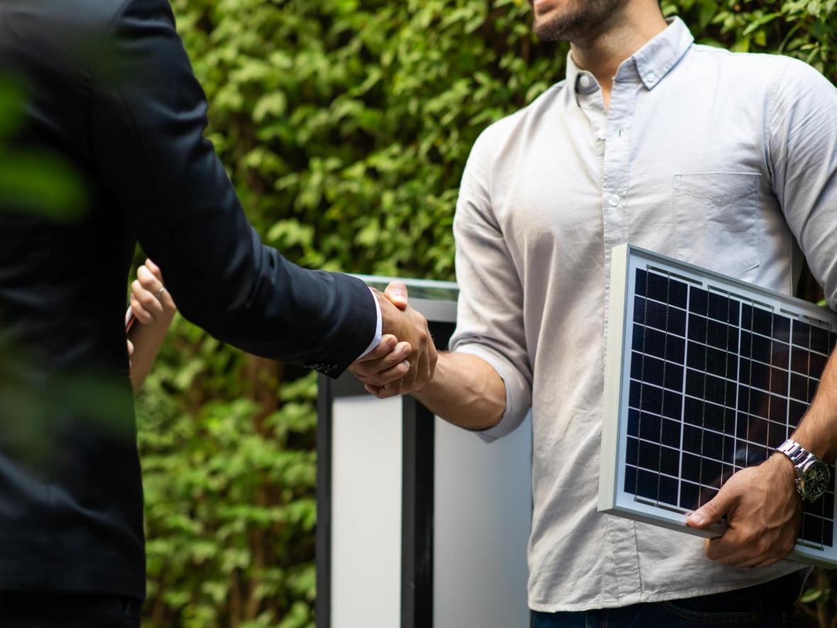 man holding solar panel shaking hand