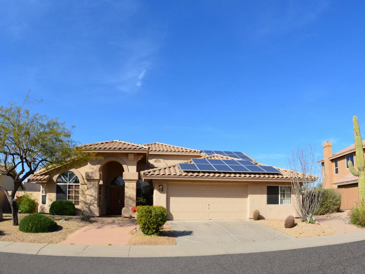 house with solar panels with driveway and cactus