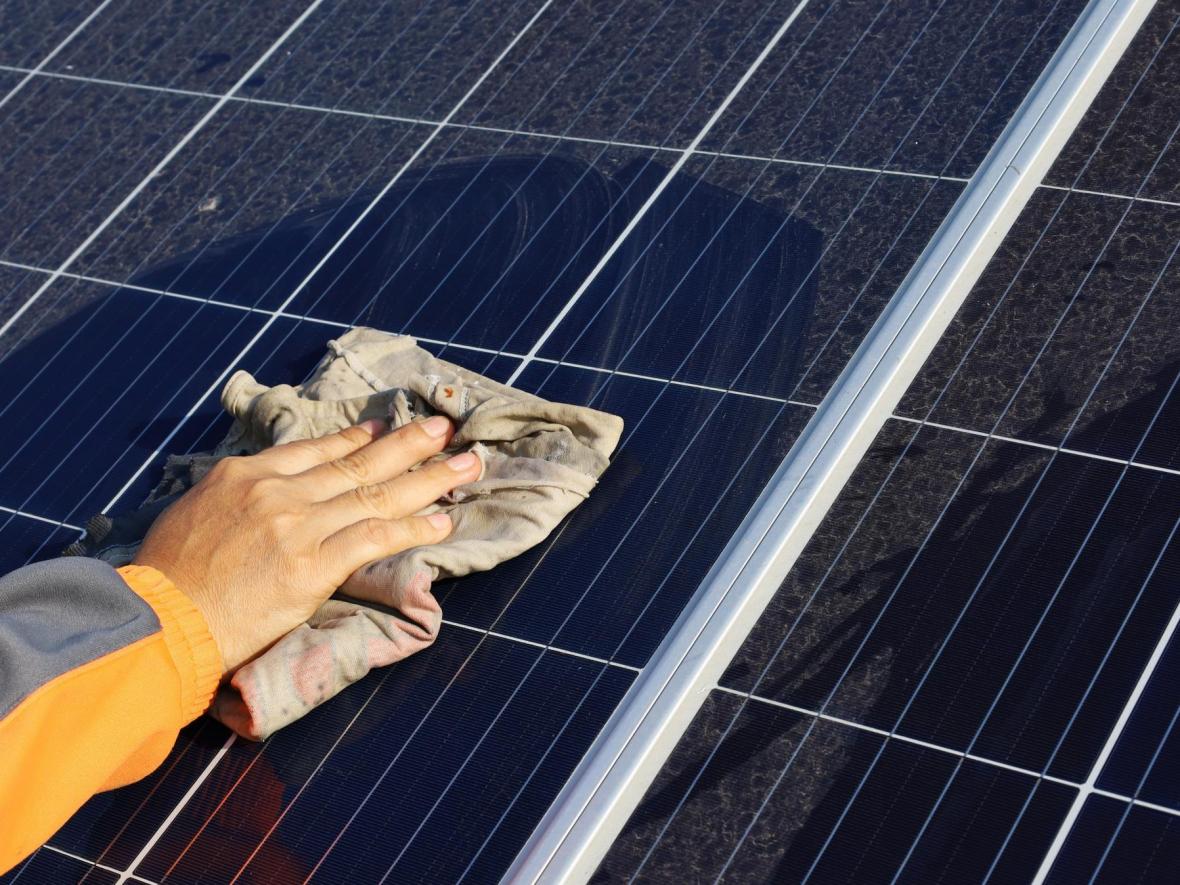 hand using cloth to wipe solar panel