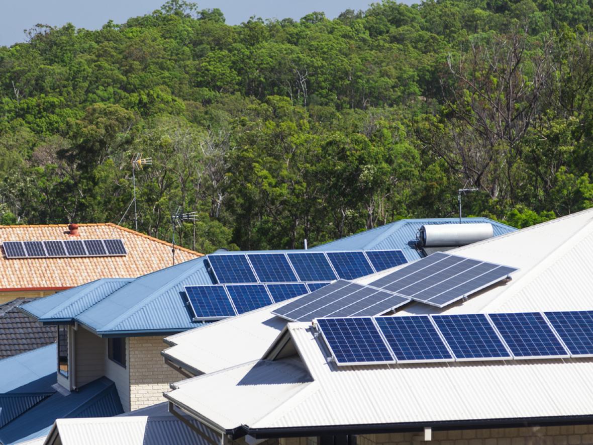 multiple solar panels on a few houses in a neighborhood