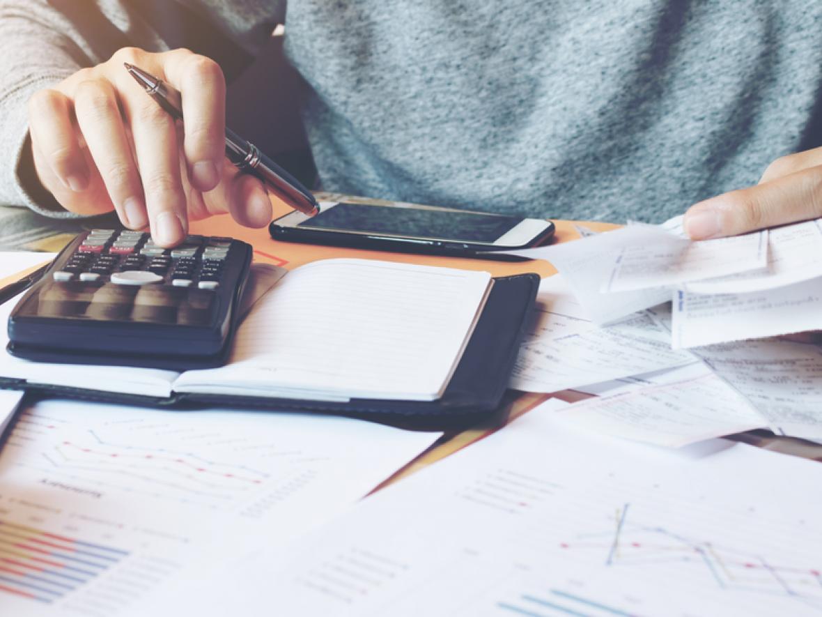 a man's hands holding a calculator and bills