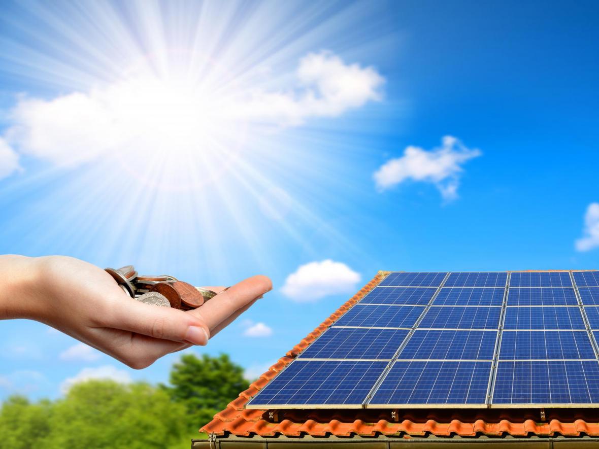 house with solar panels and hand holding money